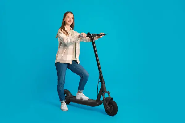 穿着浅蓝色背景的现代电动踏板车的快乐女人 — 图库照片