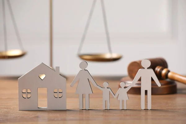 Family law. Figure of parents with children, house model, scales, gavel on wooden table, space for text