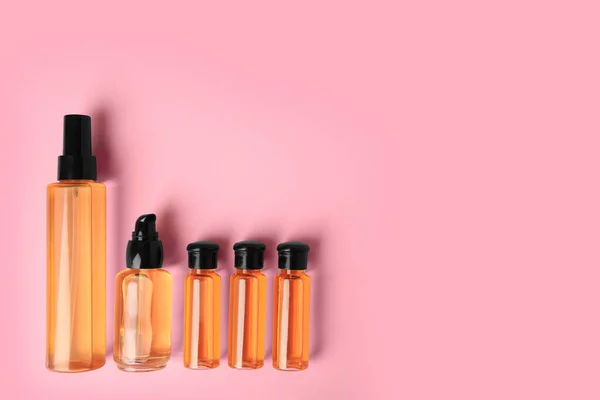 Bottles of cosmetic products on pink background, flat lay. Space for text