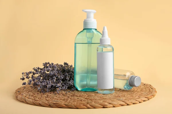 Bottles with cosmetic products and dried lavender flowers on beige background