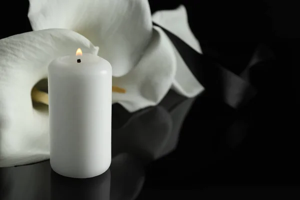 白いキャンドルと白いキャラリーの花を暗闇の中で黒いミラーの表面に燃やし テキストのためのスペースで閉じます 葬儀シンボル — ストック写真