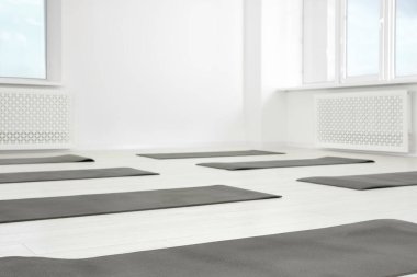 Yerde spor paspasları olan geniş bir yoga stüdyosu.