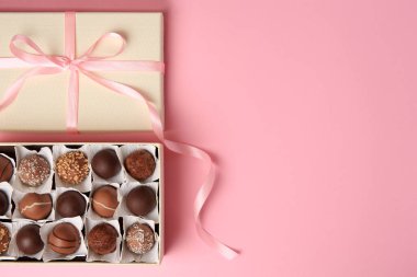 Box of delicious chocolate candies on pink background, top view. Space for text
