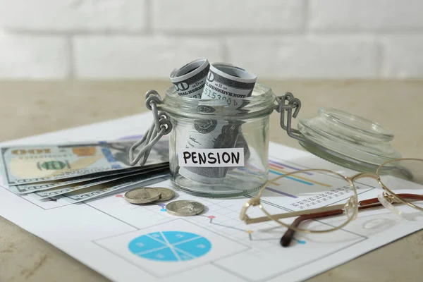 stock image Glass jar with word Pension, money, chart and glasses on beige table, closeup