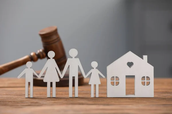 Family law. Figure of parents with children, house model and gavel on wooden table