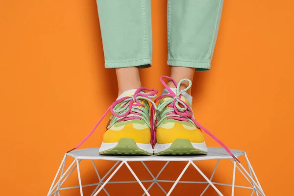 Frau Stylischen Bunten Turnschuhen Steht Auf Weißem Tisch Vor Orangefarbenem — Stockfoto
