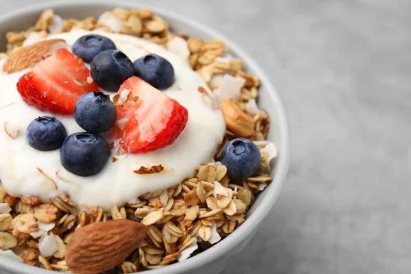 Lezzetli granola, yoğurt ve açık gri masada taze böğürtlen, yazı için yeri olan yakın plan. Sağlıklı kahvaltı.