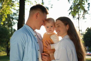 Ebeveynler ve tatlı kızları yaz günü parkta birlikte vakit geçiriyorlar.