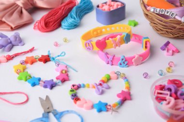 Çocuğun el yapımı takıları ve beyaz arka planda farklı malzemeler. Yakın plan.