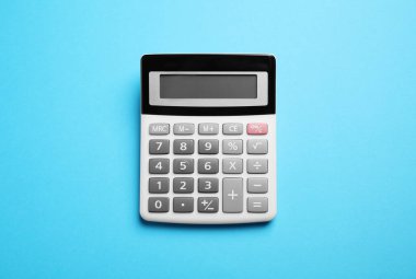 Açık mavi arkaplanda hesap makinesi, üst görünümde. Ofis ekipmanı