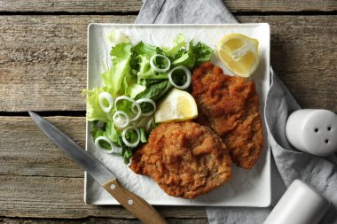 Lezzetli şnitzeller limon ve salata ile servis edilir ahşap masa, düz yatar