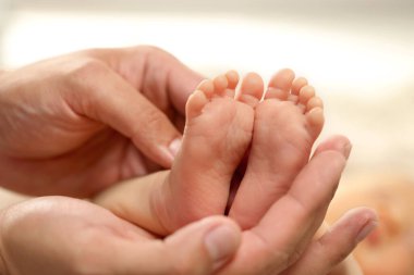 Baba yeni doğmuş bebeğini kucağında tutuyor, ayakları üzerinde yakından bakıyor. Güzel aile.