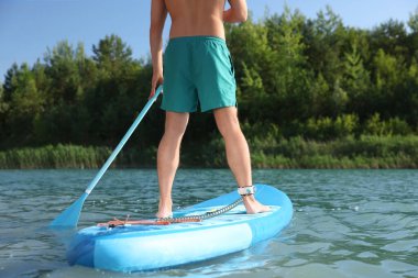 Nehirdeki SUP panosunda kürek çeken adam, yakın plan.