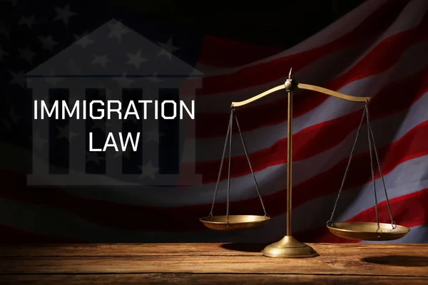 Immigration law. Scales of justice on wooden table against American flag in darkness
