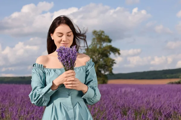 Beautiful woman with bouquet in lavender field. Space for text