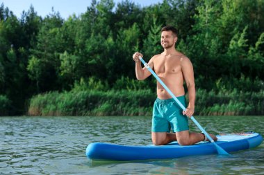 Nehirdeki SUP tahtasına kürek çeken adam.