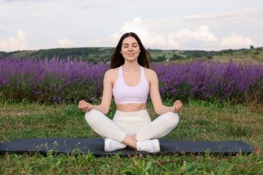 Gülümseyen kadın lavanta bahçesinde yoga yapıyor.