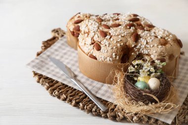 Lezzetli İtalyan Paskalya güvercini pastası (Colomba di Pasqua) ve beyaz ahşap masada dekoratif yumurtalar.