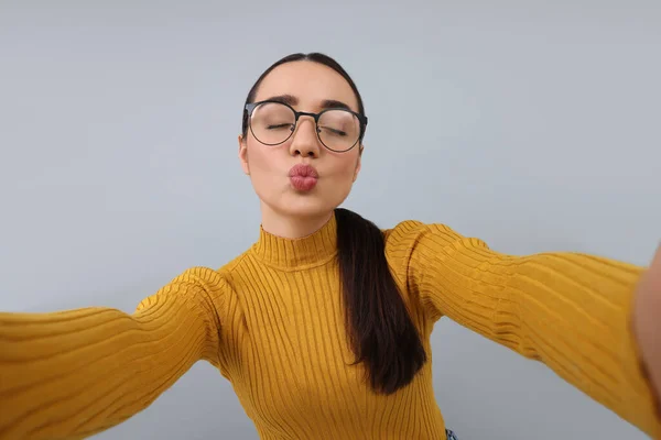 Młoda Kobieta Robi Selfie Wieje Pocałunek Szarym Tle — Zdjęcie stockowe