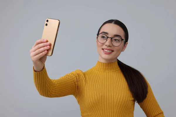 Lächelnde Junge Frau Macht Selfie Mit Smartphone Auf Grauem Hintergrund — Stockfoto
