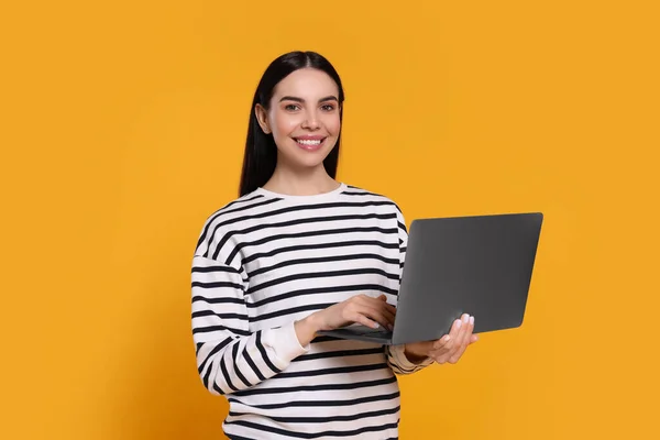 Happy woman with laptop on orange background