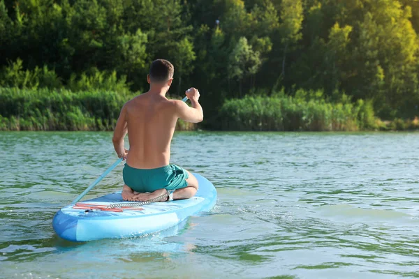 Man paddle boarding on SUP board in river, back view