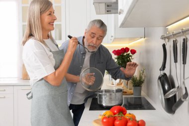 Sevecen yaşlı çift mutfakta birlikte yemek pişiriyor.