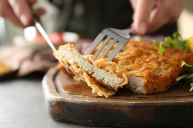 Gri masada lezzetli şnitzel yiyen kadın, yakın plan.