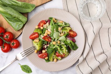 Sağlıklı yemek. Beyaz mermer masada servis edilen kinoalı, nohut ve sebzeli lezzetli salata.