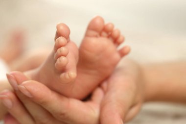 Anne yeni doğmuş bebeğini kucağında tutuyor, ayakları üzerinde yakın çekim yapıyor. Güzel aile.