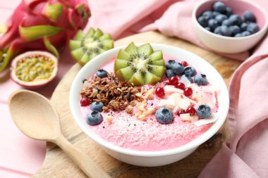 Lezzetli meyve suyu kasesi, taze kivi meyvesi, böğürtlen ve granola pembe ahşap masa, yakın plan.