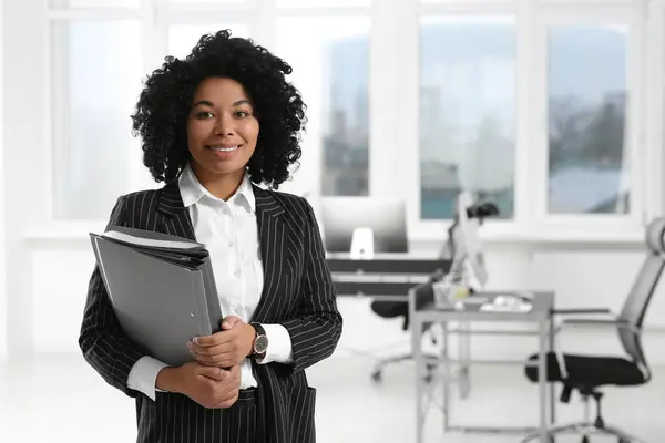 stock image Smiling young businesswoman with folders in office. Space for text