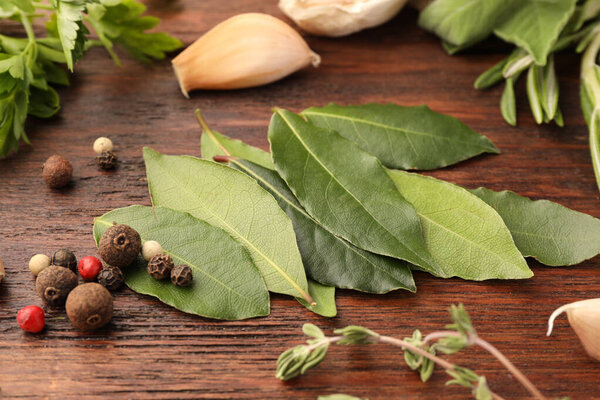 Ароматические свежие лавровые листья и специи на деревянном столе, крупный план