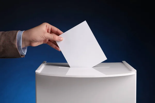 ダークブルーの背景に投票ボックスに彼女の投票を置いた女性 クローズアップ — ストック写真