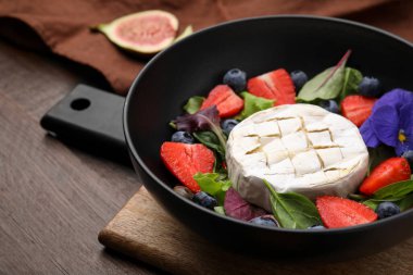 Brie peynirli lezzetli salata, ahşap masada yabanmersini ve çilek, yakın plan.