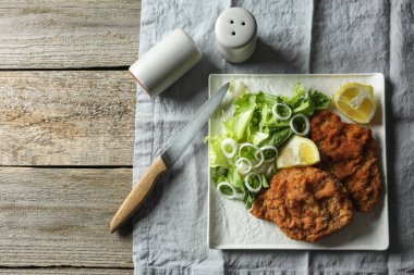 Tahta masada limon ve salata ile servis edilen lezzetli şnitzeller. Metin için boşluk