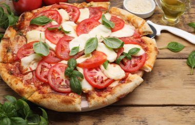 Domatesli lezzetli Caprese pizzası, ahşap masada servis edilen mozzarella ve fesleğen.