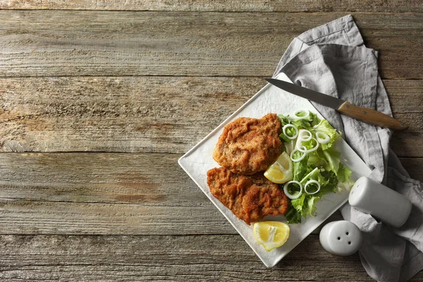 Tahta masada limon ve salata ile servis edilen lezzetli şnitzeller. Metin için boşluk