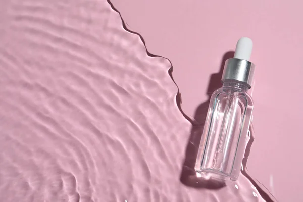 瓶装水中的化妆品油粉色背景 顶部视图 案文的篇幅 — 图库照片