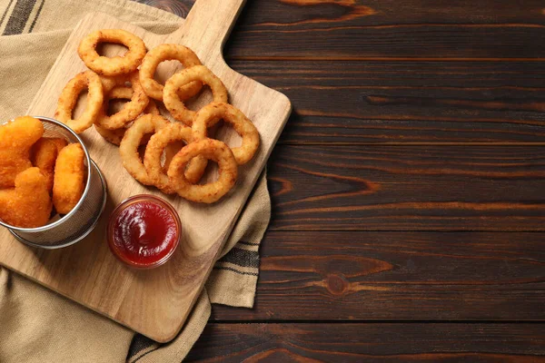 Styrelse Med Välsmakande Ketchup Kyckling Nuggets Och Lökringar Träbord Ovanifrån — Stockfoto