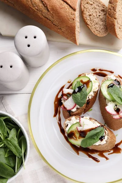 stock image Delicious bruschettas with cream cheese, vegetables, balsamic vinegar and ingredients on white table, flat lay