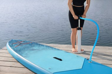 İskelede SUP panosunu dolduran kadın, yakın plan.