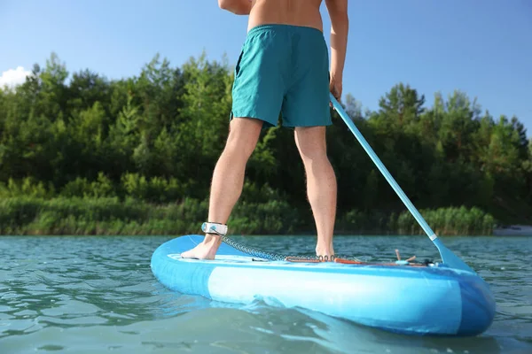 Man paddle boarding on SUP board in river, closeup