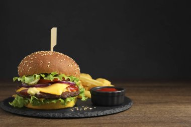 Biftek köfteli lezzetli burger, domates sosu ve ahşap masada patates kızartması, mesaj için yer.