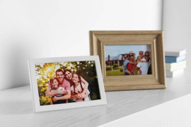Beyaz ahşap masa üzerinde aile fotoğrafları olan çerçeveler.