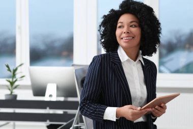 Ofiste tablet kullanan gülümseyen genç bir iş kadını. Metin için boşluk