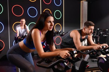 Spor salonunda egzersiz bisikleti eğitimi alan bir grup insan.