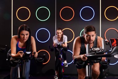 Spor salonunda egzersiz bisikleti eğitimi alan bir grup insan.