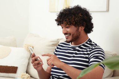 Odada akıllı telefon kullanan yakışıklı adam, mesaj için boşluk