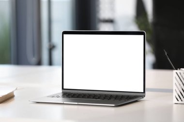 Ofisteki beyaz masada modern bir laptop. Tasarım için model